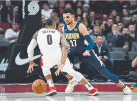  ?? Steve Dykes,
The Associated Press ?? Portland Trail Blazers guard Damian Lillard dribbles behind his back to get around Nuggets guard Jamal Murray during the first half of Monday night’s game in Portland, Ore.