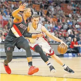  ?? PATRICK FARRELL/MIAMI HERALD ?? The Heat’s Goran Dragic drives to the basket against Portland’s Damian Lillard who lit up Miami on the offensive end for 49 points.