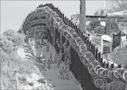  ?? [JONATHAN CLARK/NOGALES INTERNATIO­NAL] ?? Last weekend, Army troops placed additional concertina wire on the border fence in Nogales, Ariz. Nogales, Mexico, is at right.
