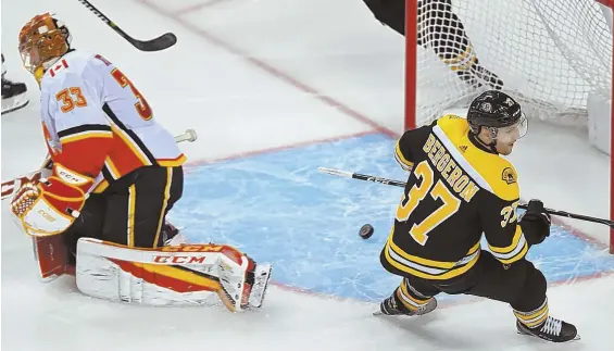  ?? STAFF PHOTO BY CHRISTOPHE­R EVANS ?? NET GAIN: Patrice Bergeron puts the puck past Flames goalie David Rittich during the Bruins' 5-2 victory last night at the Garden.