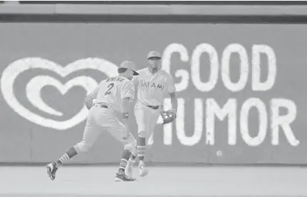  ?? WILFREDO LEE/AP ?? A pop fly by Braves right fielder Nick Markakis drops between Marlins shortstop Yadiel Rivera and left fielder Cameron Maybin in the first inning of Sunday’s game at Marlins Park in Miami.