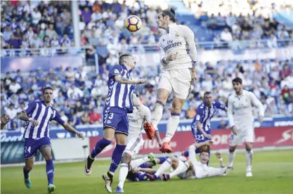  ?? — AP ?? VITORIA: Real Madrid’s Gareth Bale, jumps for the ball beside Deportivo Alaves Raul Garcia during the Spanish La Liga soccer match between Real Madrid and Deportivo Alaves, at Mendizorro­za stadium, in Vitoria, northern Spain, yesterday.