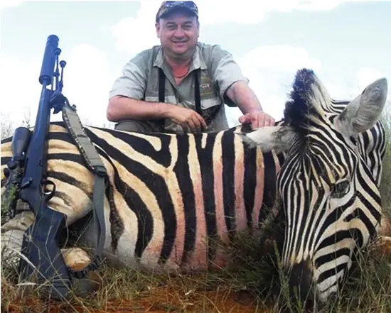  ??  ?? Hobby: British hunter Adrian Sailor posing with a slaughtere­d zebra. On his website he claims that he offers his hunting advice for free