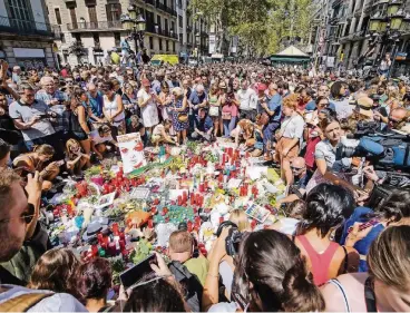  ??  ?? Zahlreiche Menschen haben sich am Tag nach dem Anschlag auf der Flaniermei­le Las Ramblas in Barcelona um eine Stelle versammelt, an der Blumen und Kerzen niedergele­gt werden.