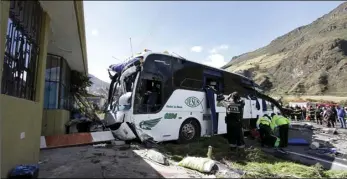  ?? AP PHOTO/CARLOS NORIEGA ?? Police and rescue workers work on a Colombian-registered bus traveling to Quito, that crashed in Pifo, Ecuador, on Tuesday. At least 24 people were killed and another 19 injured when a bus careened into another vehicle at high speed and overturned along the Pifo-Papallacta highway, near Ecuador’s capital, local officials reported.