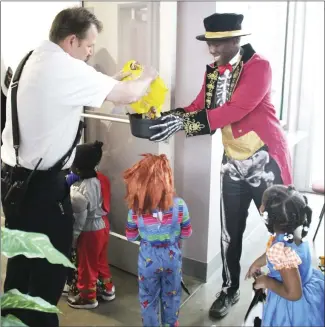  ?? Brodie Johnson • Times-Herald ?? Forrest City Fire Chief Shane Dallas refills the candy bowl for Mayor Cedric Williams this morning at city hall. Children from the ABC Preschool dressed in their Halloween costumes as they visited city hall where they were read a story, visited with officials and filled their baskets with candy.