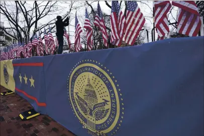  ?? DAVID PHILLIP — THE ASSOCIATED PRESS ?? A worker installs flags on Pennsylvan­ia Avenue in front of the White House ahead of President-elect Joe Biden’s inaugurati­on ceremony Tuesday in Washington.