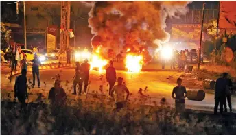  ?? — AFP photo ?? Palestinia­n protesters burn tyres amid clashes with Israeli security forces at the Hawara checkpoint, south of Nablus city, in the occupied West Bank.