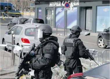  ?? PHOTOS: FRANCOIS MORI/The Associated Press ?? Police officers take position outside the kosher market where four hostages were killed earlier this month. With the deaths of three French officers during three days of terror in the Paris region and the suggestion of a plot in Belgium to kill...