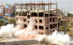  ??  ?? A thick cloud of dust envelopes the lower half of a building at Guttala Begumpet, where the GHMC attempted to implode an illegal structure.