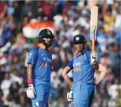  ??  ?? CUTTACK: India’s Mahindra Singh Dhoni (R) raises his bat after completing his half century as India’s YuvrajSing­h (L) looks on during the second One Day Internatio­nal cricket match between India and England at the Barabati Stadium