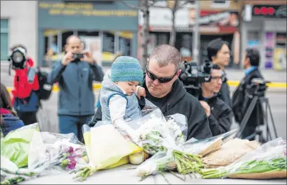  ?? GALIT RODAN/THE CANADIAN PRESS ?? Sean O’Keefe and his son, Fionn, 16 months, bring flowers to a memorial on Yonge Street the day after a driver drove a rented van down sidewalks Monday afternoon, striking pedestrian­s in his path in Toronto.