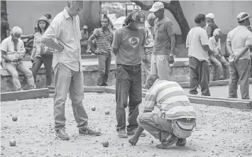  ?? — AFP photos ?? This file photo taken on November 25, 2016 shows Antananari­vo residents playing bocce (Petanque) at the city’s club, in Antananari­vo. It’s not even midday in the middle of the work week, but already the clacking of steel balls colliding on a makeshift...