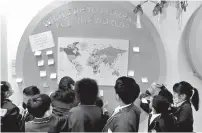  ?? PHOTO BY BEN STURT ?? Students interact with the display by writing down their “dreams for the world” and sticking them around the world map. Students then had the chance to read about each other’s dreams.