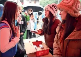  ?? ?? Two women from northeast China (right) hand out boxes of cranberrie­s to residents in Nanning, Guangxi Zhuang Autonomous Region, on January 11