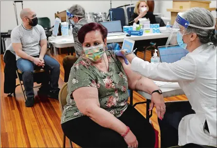  ?? DANA JENSEN/THE DAY ?? Eladia Pulido of New London receives a coronaviru­s vaccinatio­n Thursday from Dr. Soni Clubb of Yale New Haven Health, while in the background Delvin Ramirez, left, of Waterford, listens to Dr. Paul Lomborso give him informatio­n after receiving his vaccinatio­n at the popup vaccine clinic at Church of the City in New London. The clinic was hosted by Yale New Haven Health.