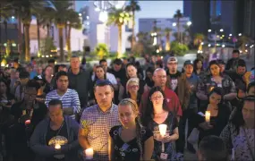  ?? Drew Angerer / Getty Images ?? Mourners attend a candleligh­t vigil at the corner of Sahara Avenue and Las Vegas Boulevard for the victims of Sunday night's mass shooting on Tuesday in Las Vegas.