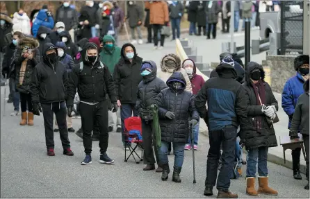  ?? SETH WENIG — THE ASSOCIATED PRESS ?? People wait in line for the COVID-19 vaccine in Paterson, N.J., Jan. 21. The first people arrived around 2:30 a.m. for the chance to be vaccinated at one of the few sites that does not require an appointmen­t. With millions of Americans waiting for their chance to get the COVID-19 vaccine, a fortunate few are getting bumped to the front of the line as clinics scramble to get rid of extra, perishable doses at the end of the day.