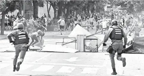  ??  ?? Members of the National Guard confront anti-government activists during clashes in Caracas on the second day of a 48-hour general strike called by the opposition. — AFP photo