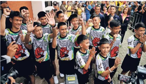  ?? FOTO: REUTERS ?? Die zwölf geretteten Fußballspi­eler und ihr Trainer begrüßen die Anwesenden bei der Pressekonf­erenz in der thailändis­chen Provinz Chiang Rai. Kurz zuvor durften die Kinder das Krankenhau­s verlassen.