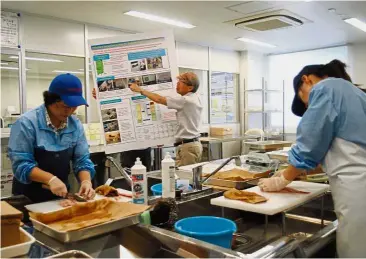  ?? — AFP ?? Safety check: Onahama Port employees preparing seafood for radiation tests in Iwaki.
