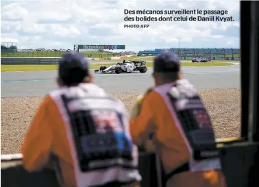  ?? PHOTO AFP ?? Des mécanos surveillen­t le passage des bolides dont celui de Daniil Kvyat.