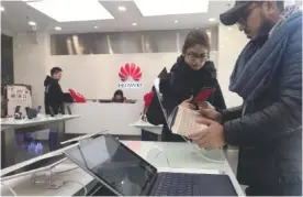  ?? AP PHOTO/NG HAN GUAN ?? Foreigners look at a Huawei computer at a Huawei store in Beijing, China, on Thursday. Canadian authoritie­s said Wednesday that they have arrested the chief financial officer of China's Huawei Technologi­es for possible extraditio­n to the United States.