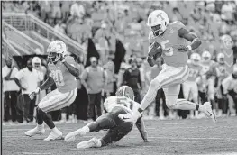  ?? WADE PAYNE AP ?? Tennessee quarterbac­k Hendon Hooker leaps over Florida linebacker Ventrell Miller en route to a touchdown during the first half Saturday in Knoxville, Tenn.