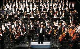  ??  ?? A file picture taken on March 16, 2015 shows Iranian conductor Ali Rahbari (center) and the Tehran Symphony Orchestra greeted by the audience after performing at the Vahdat Hall in Tehran.—AFP