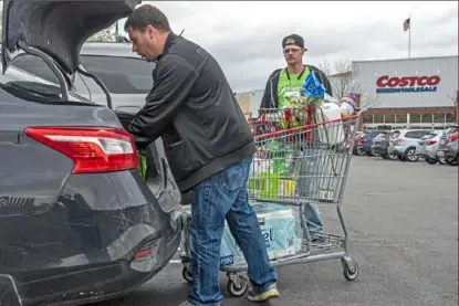  ?? Christian Snyder/Post-Gazette ?? Kevin McIntosh, of Connellsvi­lle, loads his car Tuesday with groceries to be delivered via Instacart from Costco in Homestead while fellow Instacart contractor Matthew Held, of Monroevill­e, watches on.