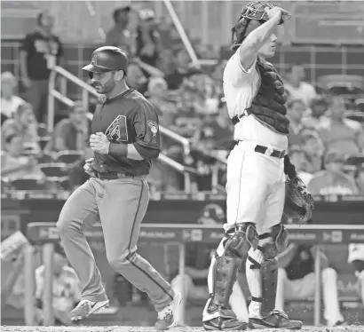  ?? LYNNE SLADKY/AP ?? The Diamondbac­ks' Daniel Descalso (left) runs past Marlins catcher J.T. Realmuto to score the go-ahead run on a single by Nick Ahmed during the eighth inning of Thursday’s game in Miami. The Diamondbac­ks won 3-2.