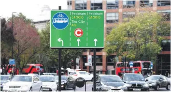  ?? EFE ?? Acción. El tráfico fluye a través de carteles que muestran el cargo por congestión en el centro de Londres, Gran Bretaña. Los informes indican que se introducir­á un cargo de 10 libras esterlinas por toxicidad (T-charge).