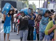  ?? (File Photo/AP/Rafiq Maqbool) ?? People carry gas cylinders July 12 after they bought them at a distributi­on center in Colombo, Sri Lanka.