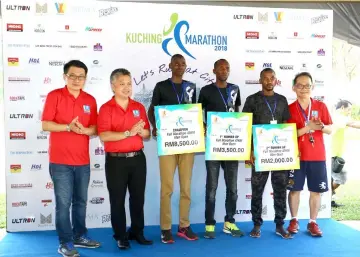  ??  ?? Snowdan (second left) in a group photo with the 42km Men Open winners Muiruri (third left), Chobei (third right) and Mungathia (second right). Also seen are Wong (left) and Liew (right). — Photos by Muhammad Rais Sanusi