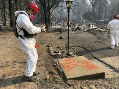  ?? SUDHIN THANAWALA — THE ASSOCIATED PRESS ?? A volunteer member of an El Dorado County search and rescue team photograph­s the orange spray paint that marks the ruins of a home to show that no human remains were found at the location in Paradise Sunday following a Northern California wildfire.