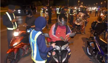  ??  ?? JPJ personnel conduct checks on motorcycli­sts during a road-block in Kuching.