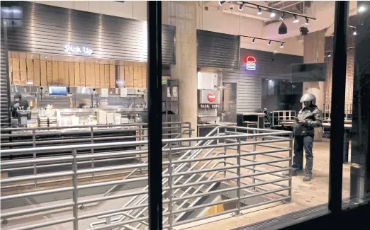  ??  ?? A delivery rider waits to pick up an order in an empty Shake Shack restaurant in Manhattan on March 18. The company, with $500 million in annual revenue, plans to apply for a new government­guaranteed small-business loan.