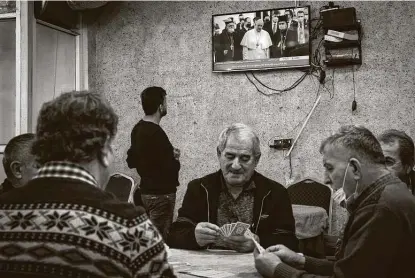  ?? Chris McGrath / Getty Images ?? Men play cards at a tea house in Irbil, Iraq, in front of a television showing live footage of Pope Francis on Friday. His primary aim over the weekend is to encourage Iraq’s Christian population to stay and help rebuild the country devastated by wars and strife.