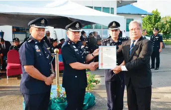  ?? — Photo by Abang Ismail Abang ?? Batholomew (second left) presents a certificat­e of appreciati­on to a retired policeman. Su’ud