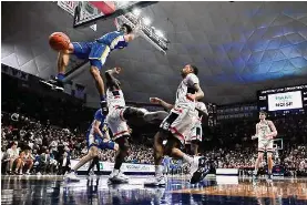  ?? Jessica Hill/Associated Press ?? Xavier’s Desmond Claude dunks over UConn’s Adama Sanogo, left, and Jordan Hawkins, right, in the first half on Wednesday in Storrs.