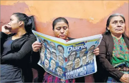  ?? / S. M. (REUTERS) ?? Una mujer lee el periódico a las puertas de un colegio electoral, ayer en Ciudad de Guatemala.