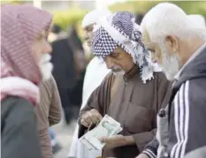  ??  ?? Iranian tourists exchange Iranian rial banknotes in the central Iraqi shrine city of Najaf on Tuesday. — AFP