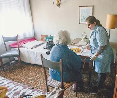  ??  ?? Deolinda ajuda Maria das Dores, 77 anos, a sentar-se na mesa para depois lhe dar a refeição e m