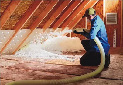  ?? COURTESY OF GARRITY INSULATION ?? A Garrity staff member blows insulation into an attic space.