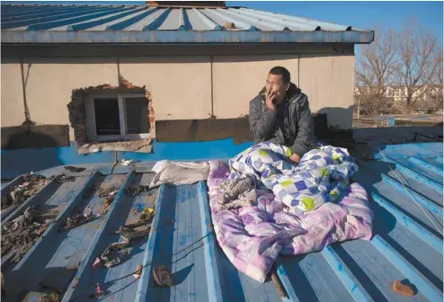  ?? NICOLAS ASFOURI AGENCE FRANCE-PRESSE ?? Un travailleu­r migrant se repose sur le toit de la maison dont il a été évincé dans un village des environs de Pékin.