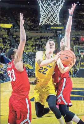  ?? Tony Ding / AP ?? Michigan’s Duncan Robinson (22) weaves past Ohio State defenders Keita Bates-Diop (33) and Kyle Young to shoot during the first half of the game in Ann Arbor, Mich.