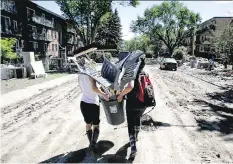  ?? LYLE ASPINALL ?? Volunteers carry shovels and brooms donated by Rona in the flood-stricken Mission area of Calgary on June 26, 2013. Many are concerned not enough has been done since then to prevent future floods