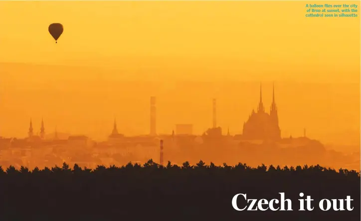  ??  ?? A balloon flies over the city of Brno at sunset, with the cathedral seen in silhouette