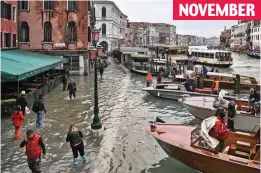  ??  ?? Swamped: Tourists wade through a flooded embankment