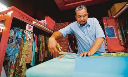  ?? [FOTO SUPIAN AHMAD/BH] ?? Zainal Abidin sibuk memotong kain bagi menyiapkan tempahan pelanggan di kedainya Shyza Design, di Medan MARA, Kuala Lumpur.